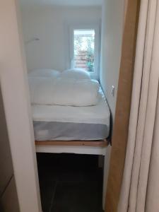 ein kleines Bett in einem kleinen Zimmer mit einem Fenster in der Unterkunft Hameau du Puech, rez-de-jardin avec parking et clim in Cap d'Agde