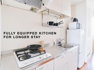 a white kitchen with a stove and a sink at Evergreen Apartment Hotel in Tokyo
