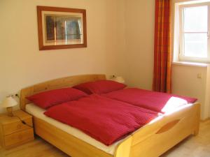 a bedroom with a bed with red sheets and a window at Pension Sarstein in Hallstatt