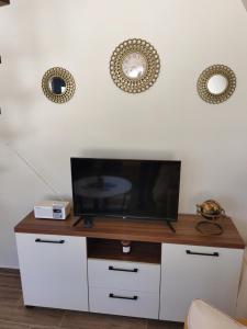 a tv on a white cabinet with a clock on the wall at Tara 1395 Altitude in Sekulić  +14 photos