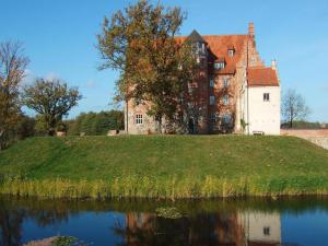 an old castle on a grassy hill next to a body of water at Ferienwohnungen am Flacher See, Klocksin in Klocksin