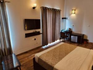a bedroom with a bed and a desk and a television at Ganret suites and resort in Vrindāvan