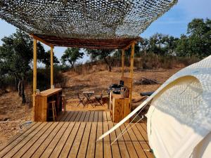 a wooden deck with a table and a tent at La tente Gecko in São Luis