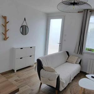 a living room with a couch and a table at petite maison 3km de la mer in Ozeville