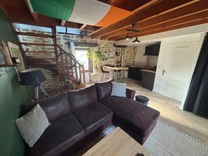 a living room with a leather couch and a kitchen at Charmant appartement au Faouët in Le Faouët