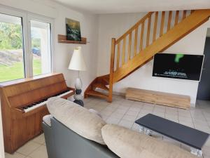 a living room with a couch and a piano at Entre terre et mer in Plédran