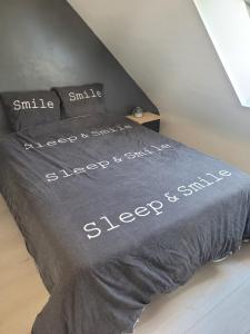 a bed with the words sleep and smiles written on it at Entre terre et mer in Plédran