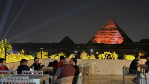 a group of people sitting at tables looking at the pyramids at Zuri Pyramids View Hotel in Cairo