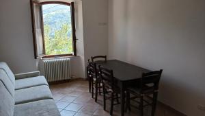sala de estar con mesa, sofá y ventana en La Voltata, en Pianosinatico