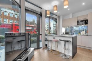 a kitchen with a stove and two bar stools at New Modern Apartment near Heathrow Airport in Yiewsley