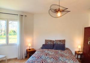 a bedroom with a bed and a chandelier at La petite maison de Valérie proche château de la Rode, du Domaine de Flore et du Lac Saint Ferréol in Lempaut +28 photos