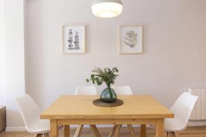 una mesa de comedor con sillas blancas y un jarrón. en La Ventana de Formigal by BeValle, en Formigal