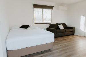 a bedroom with a large bed and a couch at The Paddock at Ulupna - The Paddock at Ulupna - 10 minutes from Cactus Country in Ulupna