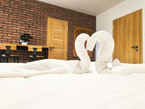 a bed with white sheets and swans forming the wordlove at Penzión Dovalovec in Liptovský Hrádok +23 photos