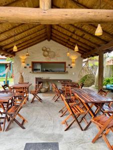 a group of wooden tables and chairs under a pavilion at Casa 02 na villa uryah in Caraíva