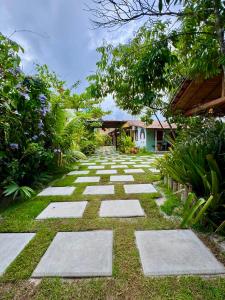 a garden with stepping stones on the grass at Casa 02 na villa uryah in Caraíva +11 photos