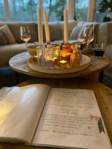 een tafel met een boek en kaarsen en wijnglazen bij Chalet 228 in Durbuy