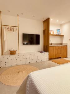 萨尔瓦多IorubaStudio的卧室配有白色瓷砖墙壁上的电视