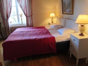1 dormitorio con 1 cama con manta roja y 2 lámparas en Tössestugan en Tösse