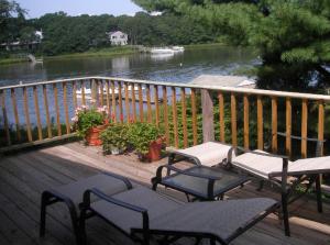 a deck with two chairs and tables and a river at Waterfront house in Falmouth +7 photos