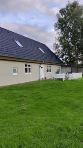 a white house with a fence and a green yard at Rosengård in Hammel