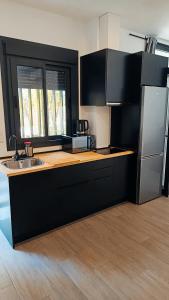 une cuisine avec des armoires noires et un réfrigérateur en acier inoxydable dans l'établissement Apartamentos Trastamara, à Séville
