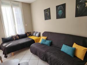 a living room with a black couch and a yellow blanket at RDC 1 chambre-centre-ville-terrasse in Vitry-le-François