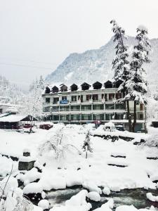 a snow covered building in front of a mountain at Hotel Satkar Residency in Manāli