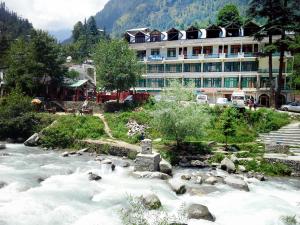 a river in front of a hotel with a building at Hotel Satkar Residency - Riverside Old Manali in Manāli