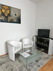 a living room with two chairs and a glass table at Cozy apartment near hockey & football arena in Trnávka