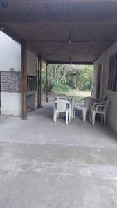 un patio con sillas blancas y una mesa en un edificio en Casa de Playa - 6 Personas, en Balneario Pehuén-Có 1 foto más