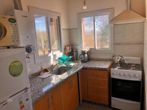 a kitchen with a sink and a stove at Cabaña EL GALLO in Villa General Belgrano