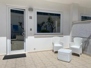 Un patio con sillas blancas y una ventana. en Il borghetto tranquillo, en Albano Laziale