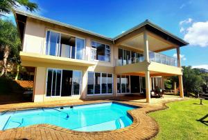 a house with a swimming pool in front of it at The Big 5 Golfhouse in Southbroom
