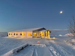 a house in the snow with lights on at Lambastadir Guesthouse in Selfoss +37 photos