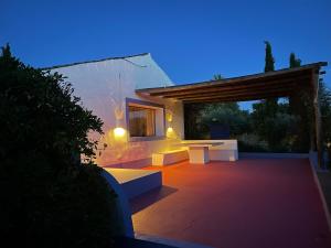 a patio with two tables and benches at night at Courela do Monte Novo in Monte de Jangeis de Cima