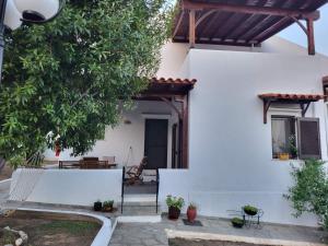 Casa blanca con un árbol y un patio en Casa De Vacacion, en Gerakini