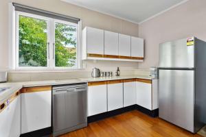 a kitchen with white cabinets and a stainless steel refrigerator at Charming 3 Bedroom Family Home Pet Friendly in Hamilton