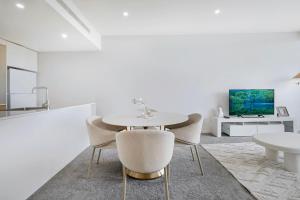 a white dining room with a white table and chairs at Stylish 1Bed Next to Macquarie Centre & Metro in Sydney +9 photos