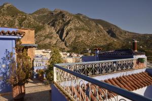 a balcony with blue buildings and mountains in the background at Dar Aldea in Chefchaouen
