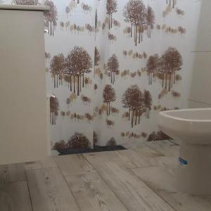 a bathroom with a wall with trees and a toilet at La Serena in María Grande