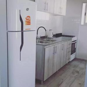 a white kitchen with a refrigerator and a sink at La Serena in María Grande +3 photos