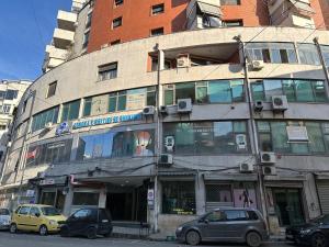 a tall building with cars parked in front of it at Meko Apartments in Tirana