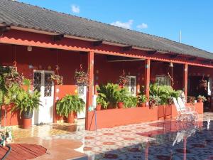 a red building with potted plants on a patio at Quinta Rubi in Las Rosas