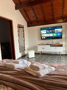 Un dormitorio con una cama grande con un televisor en la pared. en Casa marcius, en Monte Verde