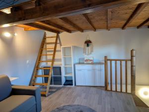 a living room with a ladder and a kitchen at Ancienne maison de bourg in Plauzat