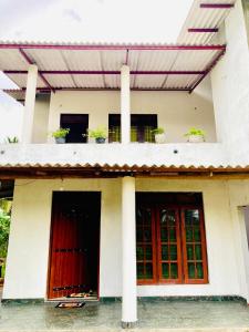 una casa con porte rosse e un balcone con piante in vaso di Yu Home Stay Anuradhapura a Anuradhapura