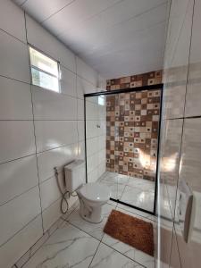 a bathroom with a toilet and a glass shower at Chalé Roda Dágua B in Alto Caparao
