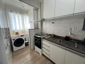 a kitchen with a stove and a sink and a microwave at Aconchego no Canto do Forte - Ar Condicionados - Tvs Grandes - Wi-fi e Estacionamento Incluso! in Praia Grande