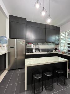 a kitchen with a refrigerator and a counter with stools at Idaman Maya in Kluang
